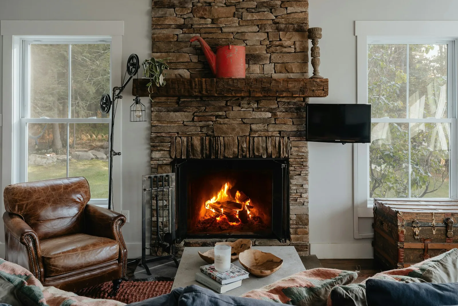 Cozy living room with a wood fire in a stacked-stone fireplace, leather armchair