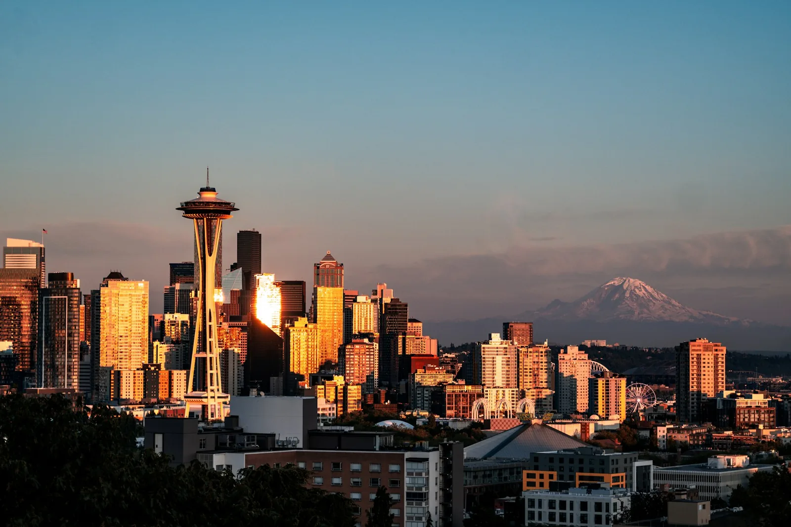 Seattle skyline and Space Needle glowing at sunset with Mount Rainier beyond